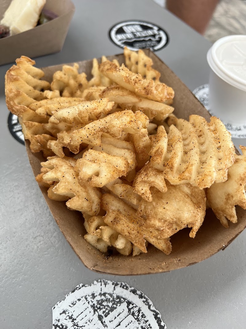 Golden waffle fries seasoned with spices in a brown takeout boat at a casual Big Bend National Park eatery.
