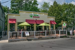 Open-air dining at a cafe-style storefront with lime-green umbrellas in Acadia National Park, along a small street.