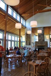 Cozy dining room at Jordan Pond House in Acadia National Park features large windows and wooden beams.