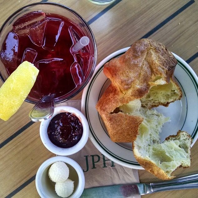 Jordan Pond area dining scene in Acadia National Park with bread, jam, and a red beverage on a sunny table.