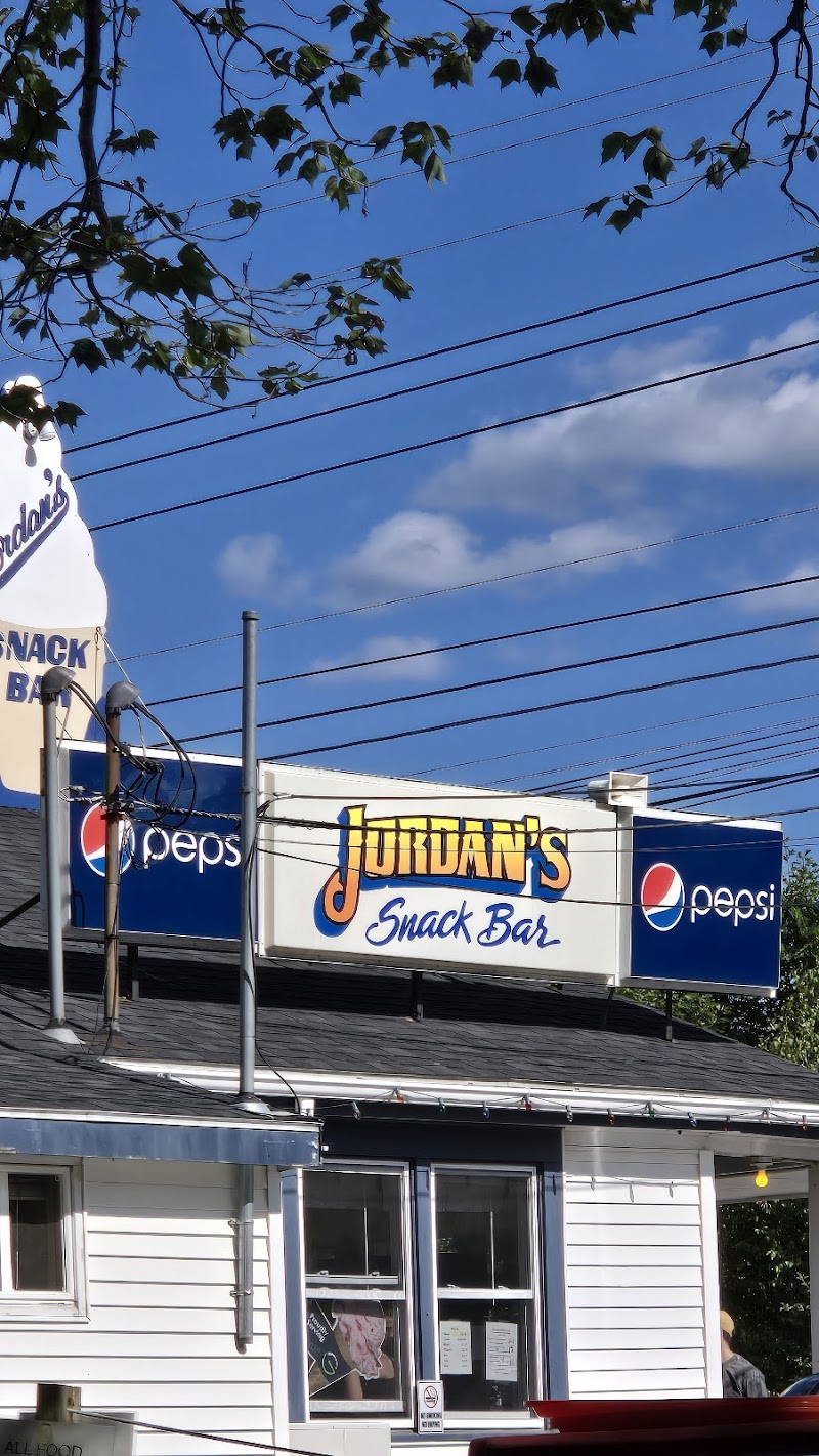 Snack bar storefront on a sunny day in Acadia National Park, featuring a white building and blue-branded signage beneath a clear sky.
