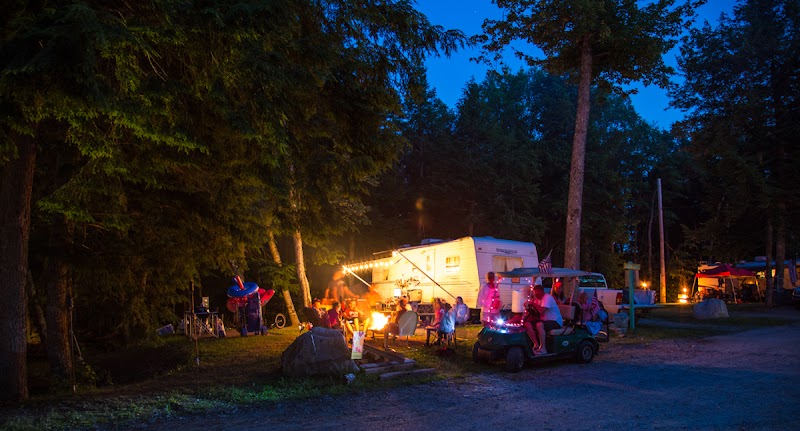 Patten Pond area campground in Acadia National Park at dusk, tents and RVs around a warm campfire.