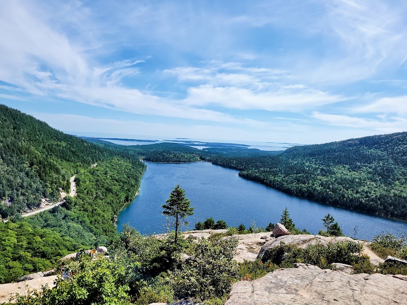 Overlook from North Bubble Trailhead in Acadia National Park, a blue lake framed by forested hills and rocky ledges.