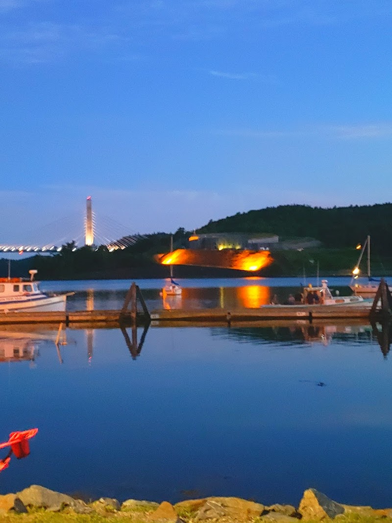 Bucksport harbor at dusk in Acadia National Park, boats swaying gently as reflections shimmer on the calm water.