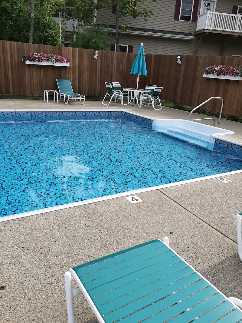 Outdoor pool area at lodging near Acadia National Park with turquoise water and lounge chairs.