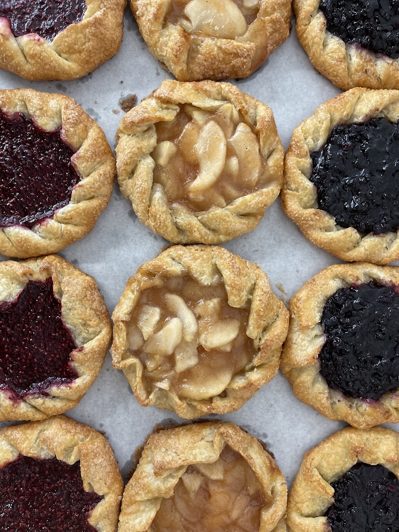 Assorted fruit galettes with braided golden crusts—peach, apple, and berry varieties on parchment in Acadia National Park.