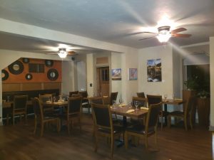 Cozy dining room with wooden tables and chairs, wall art, and warm lighting in Arches National Park area.