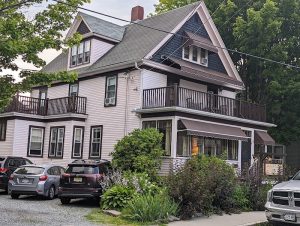 Lodge-style residence with a wraparound porch and lush greenery in Acadia National Park.