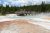 Boardwalk curves over a steaming geothermal pool at Lewis Falls in Yellowstone National Park.