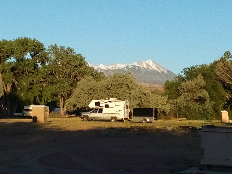 Campground in Arches National Park with RVs and distant snow-capped mountains.