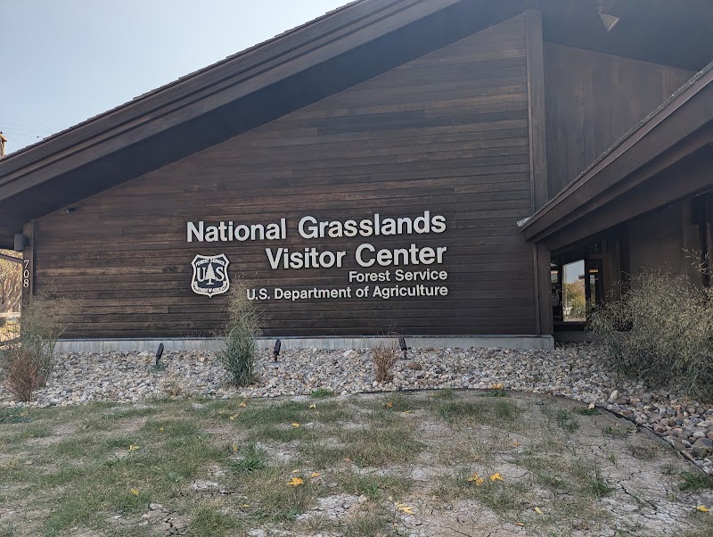 Wooden lodge-style visitor center with a sloped roof and stone edging, at Badlands National Park.