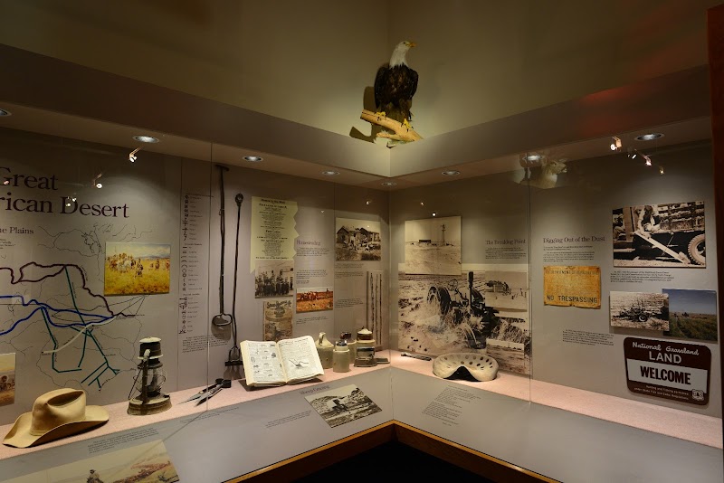 Exhibit-filled visitor center displays a mounted eagle, vintage hats, maps, old tools, and historical photos for Badlands National Park.