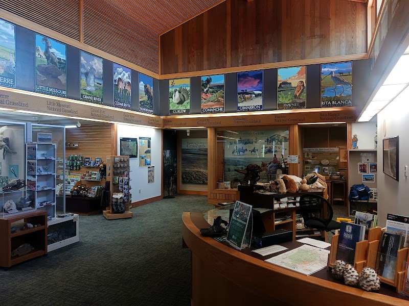 Interior of a visitor center at Badlands National Park with a curved front desk, brochure racks, and wall banners.