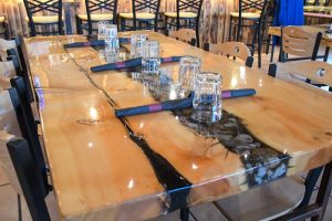 Interior of a Yellowstone restaurant with a long wooden table set for guests, glassware and cloth napkins along the center.
