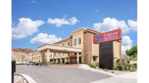 Hotel exterior with a porte-cochere entry, beige brick facade and a red sign; near Arches National Park.