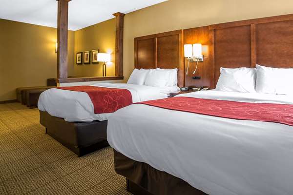 Two queen beds with white linens and red runners in a wood headboard hotel room, Arches National Park area.