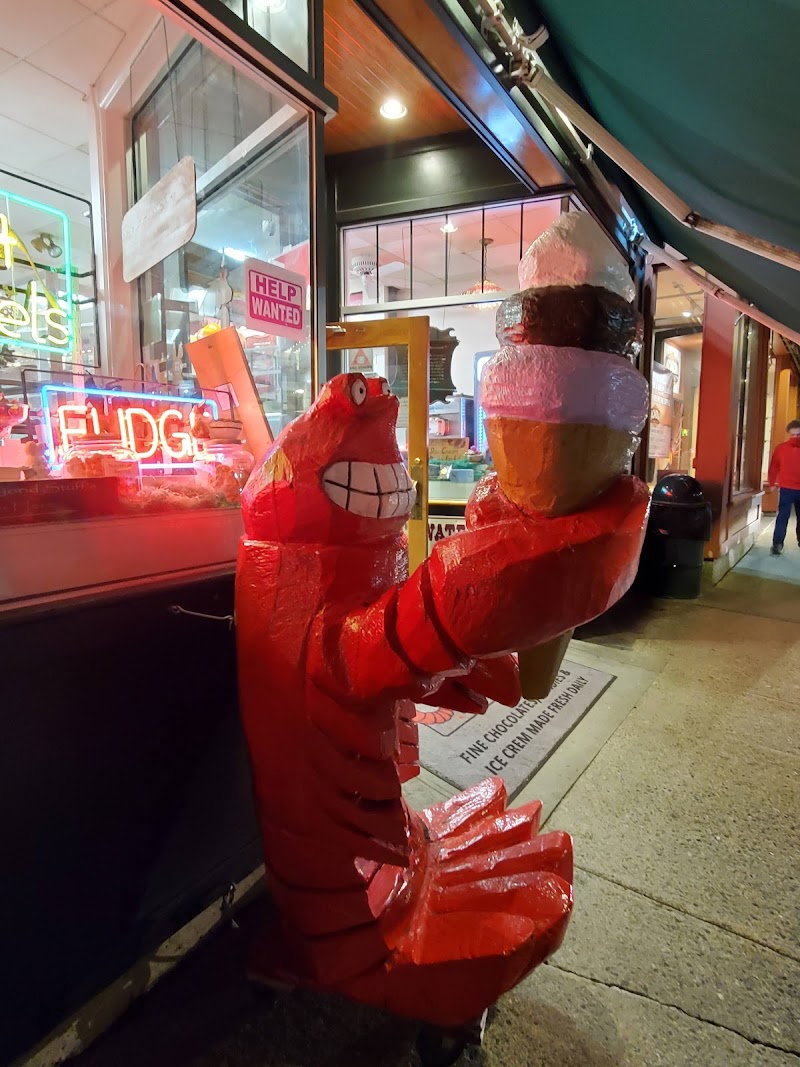 Bright red lobster statue with a giant ice cream cone stands outside a neon-lit shop in Acadia National Park.
