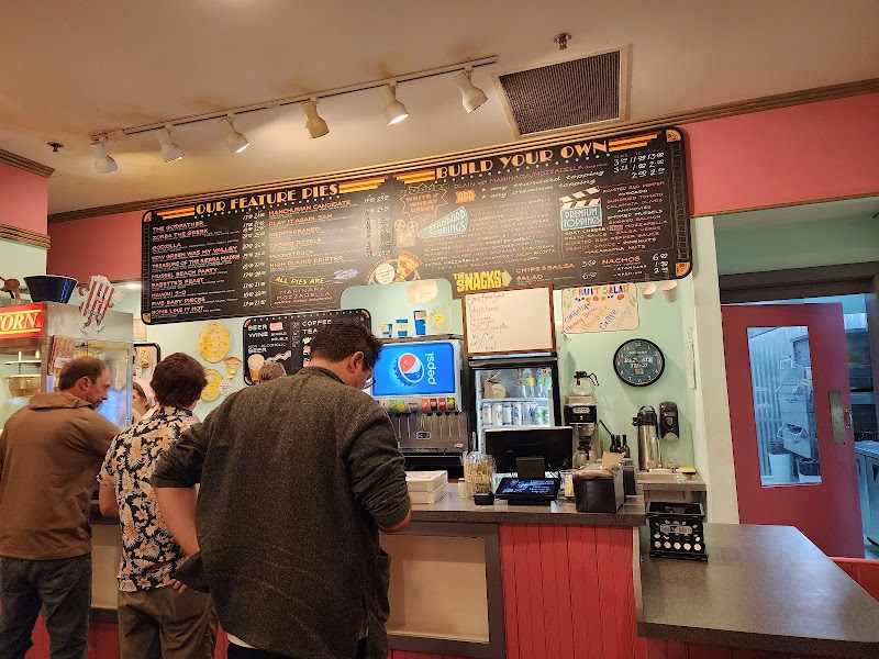 Inside a retro-style cafe in Acadia National Park, customers queue at a counter beneath a large chalkboard menu.