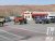 Parking lot with orange and blue off-road jeeps in front of a diner with a red awning, Arches National Park desert cliffs in the background.