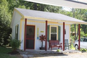 Fort Knox site in Acadia National Park shows a small colorful cabin-style building on a shaded campground.