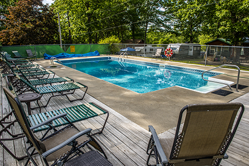 Fort Knox campground pool at Acadia National Park surrounded by lounge chairs and a wooden deck.