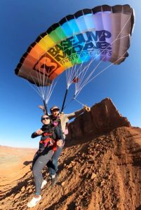 Paragliders launching from a cliff in Arches National Park, Moab, Utah, above rugged red rock formations.