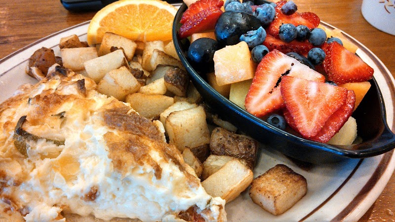 Riverside Cafe breakfast at Acadia National Park with eggs, potatoes, and a fresh fruit bowl including strawberries and blueberries.