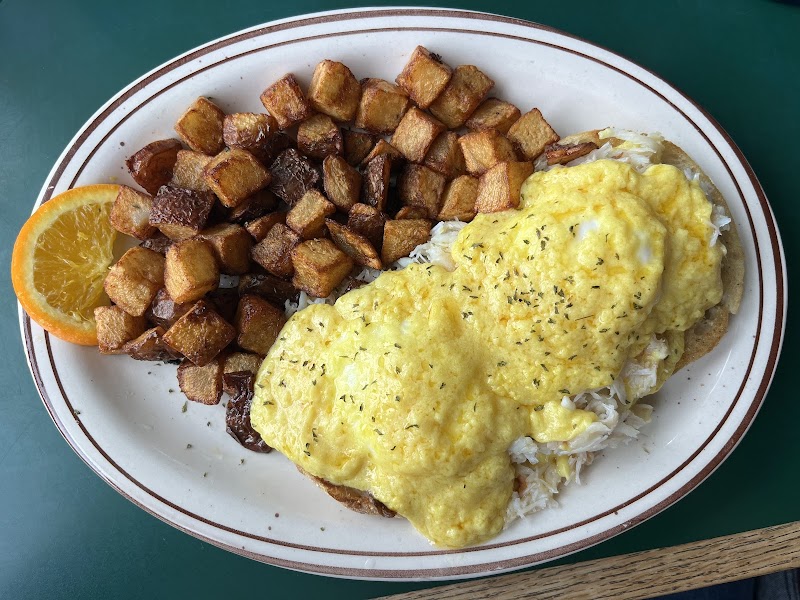Breakfast plate with scrambled eggs and hash browns, served alongside an orange slice in Acadia National Park.