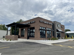 Brick coffee shop storefront in Yellowstone National Park near Mammoth with large windows and outdoor seating.