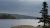 Blue Hill Harbor in Acadia National Park seen from a rocky overlook with boats on the calm water under a cloudy sky.