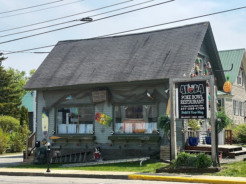 Weathered wooden restaurant with surfboards on its exterior and a signboard beside, in Acadia National Park.
