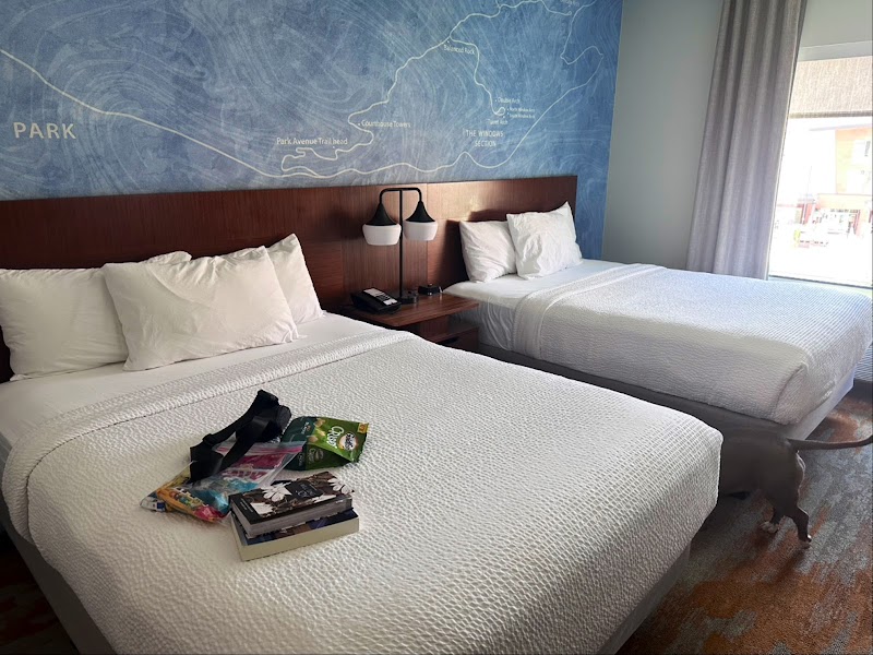 Two queen beds with white bedding, a blue Arches National Park map mural on the wall, and a nightstand between them.