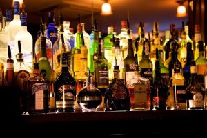 Assorted liquor bottles line a warmly lit bar shelf with colorful labels under amber lighting, Acadia National Park.