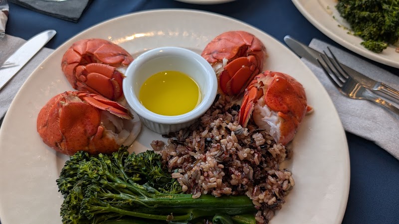 Lobster tails arranged on a plate with wild rice, steamed broccoli, and a ramekin of melted butter at Acadia National Park.