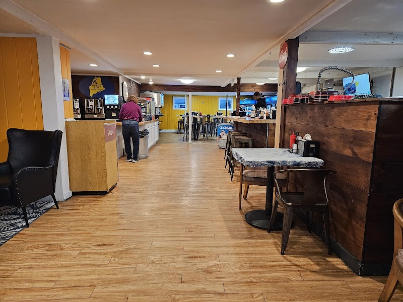Inside a cozy cafe in Acadia National Park featuring wooden floors, yellow walls, a service counter, and booths plus tables.
