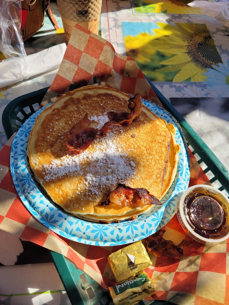 Stack of pancakes with bacon, powdered sugar and syrup on a blue patterned plate at Acadia National Park.