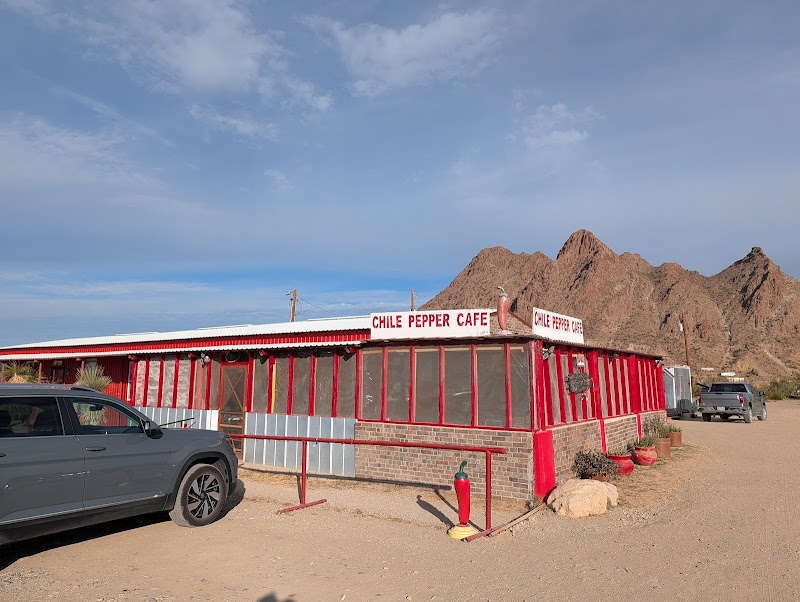 Red-walled cafe building beside a dusty road in Big Bend National Park with rugged mountains in the background.