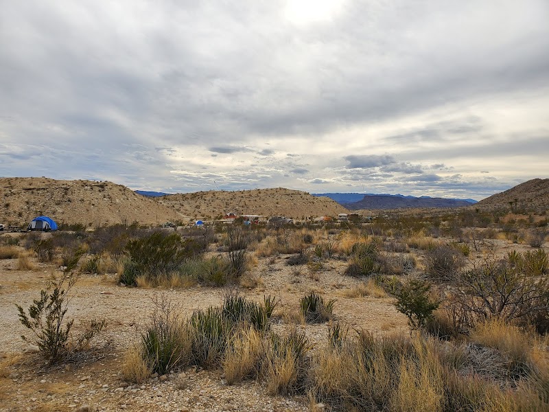 Desert campground scene in Big Bend National Park with tents set among sagebrush and rocky hills.