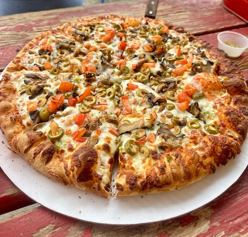 Slice of veggie pizza from Long Draw area dining spot in Big Bend National Park, Texas, resting on a rustic wooden table.