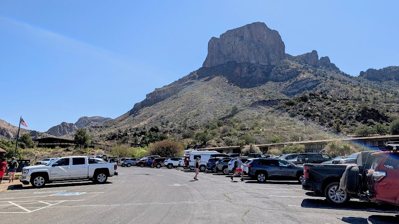 Parking lot at the Chisos Mountains area in Big Bend National Park, with rugged peak silhouetted against a clear blue sky.