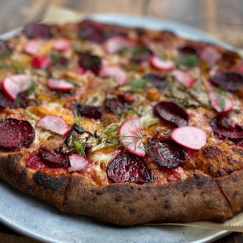 Beet and radish-topped pizza with herbs on a rustic crust, served near Ellsworth, Maine, gateway to Acadia National Park.