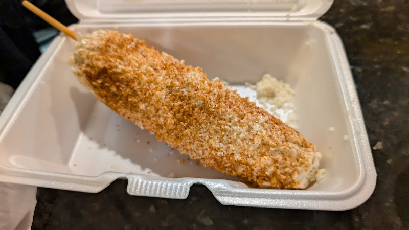 Breaded, fried corn on a stick with a crispy coating rests in a white takeout container at Arches National Park.