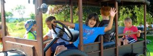 Children ride in a vintage car at Seal Cove within Acadia National Park, enjoying a sunny day.