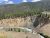 Earthquake Lake, Yellowstone National Park: steep eroded hillside, pine rim, and a rushing river through the basin.
