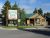 Rustic wooden lodge with a green metal roof sits beside a large sign near a park road in Yellowstone National Park.