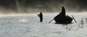 Sedgwick fishing at dawn along Acadia National Park shoreline with a small boat nearby.