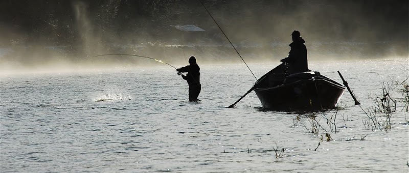 Sedgwick fishing scene on a calm lake in Acadia National Park, Maine, with a lone angler casting near a small boat.