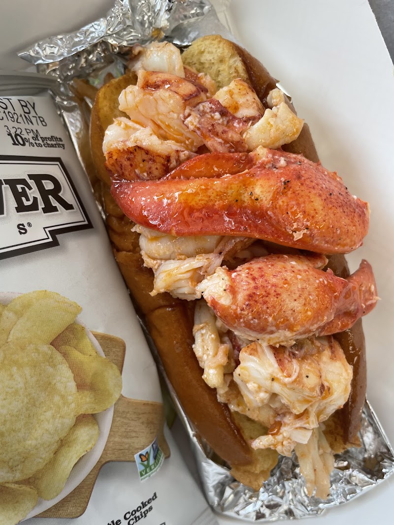 Lobster roll packed with chunky lobster meat in a toasted bun, foil wrap, and a side of potato chips, Acadia National Park.