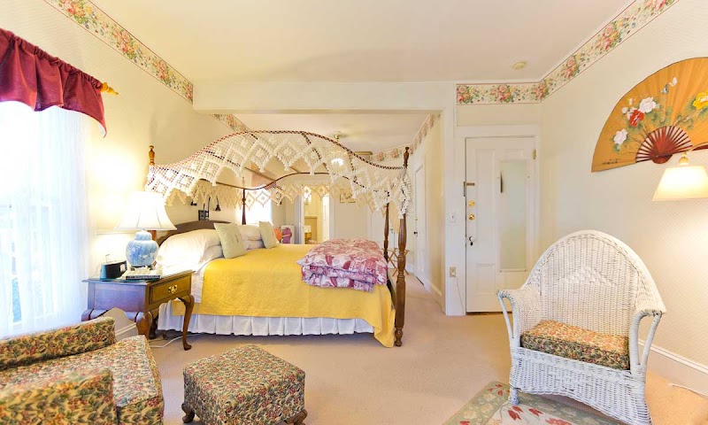 Cozy lodge bedroom with a four-poster bed, lace canopy, and yellow duvet at Acadia National Park.