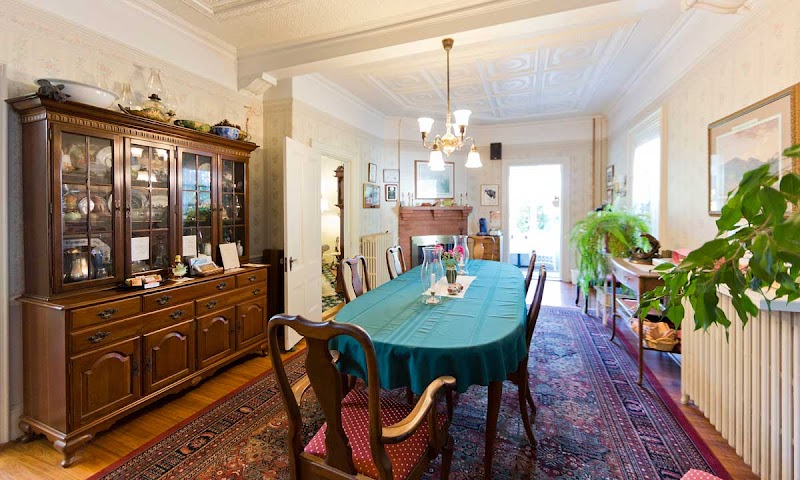 Spacious dining room with a teal tablecloth, china cabinet, chandelier, and potted plants in a cozy Acadia National Park lodging.